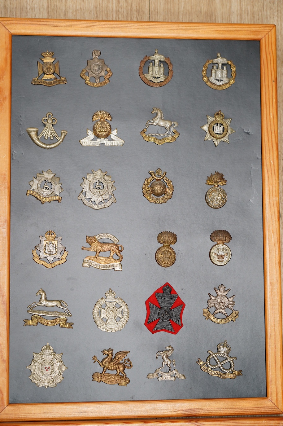 A collection of ninety-five military cap badges mounted on four boards including; The Reconnaissance Corps, RAEC, Royal Engineers, Small Arms School, Royal Warwickshire 1st Birmingham Battalion, Royal Army Medical Corps,